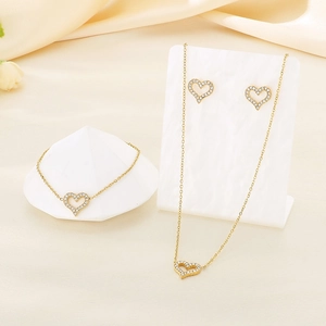Detailed view of golden heart-shaped jewelry set with micro-pave crystals on silk