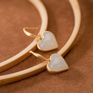 Dettaglio di orecchini a cuore in giada bianca con bordi in oro opaco e ganci classici