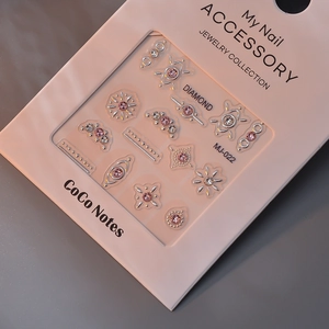 Detail of 3D embossed nail stickers featuring pink rhinestones and metallic frames