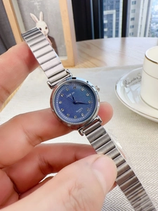 Close-up of a silver steel quartz watch featuring a navy blue dial with rhinestone markers