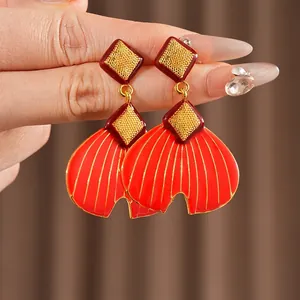 Minimalistische rote Fächerohrringe mit goldenen Rautensteckern in einer Makroansicht