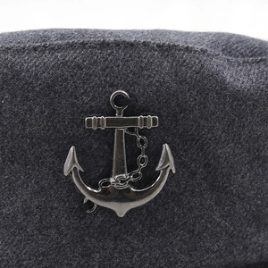 Détail d'un badge ancre en métal noir argenté sur la texture de feutre gris d'un chapeau