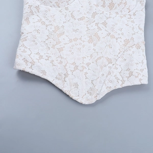 Close-up of intricate white lace embroidery and delicate knit texture on a corset top