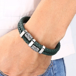 Gros plan sur un bracelet en cuir tressé vert multicouche avec charmes en métal gravés