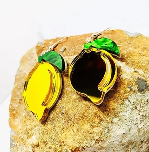 Macro shot of yellow and green acrylic lemon earrings on a natural stone background