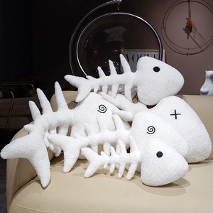 Three sizes of white fishbone plush pillows with unique eye embroidery on a sofa
