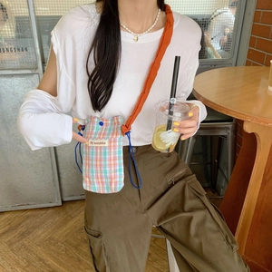 Detail of checkered mini crossbody phone bag with drawstring closure and orange strap