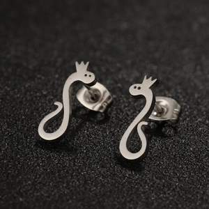 Macro shot of silver snake earrings with crown detail on a black textured surface