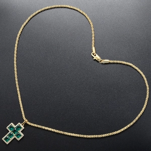 Golden corn chain with cross pendant shaped into a heart on dark textured background