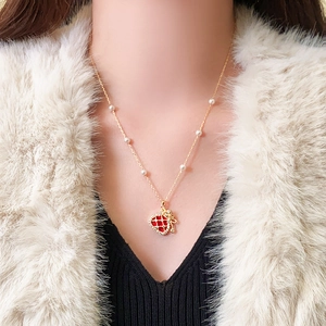 Close-up of a gold-plated necklace with a red strawberry pendant and white pearls