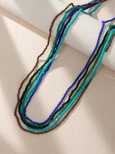 Detail view of five bohemian handmade seed bead chains in vibrant multicolor on a white stand