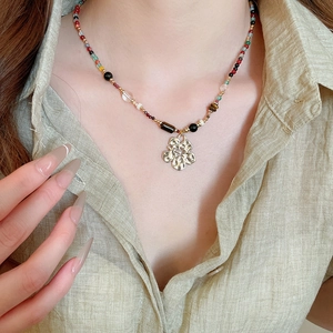 Detail of bohemian colorful beaded necklace with a textured golden flower pendant
