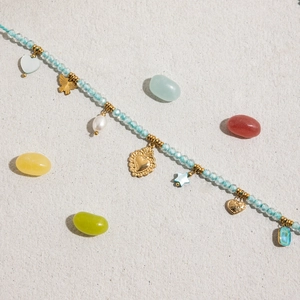 Detail of beaded necklace with gold heart and butterfly charms on blue faceted beads
