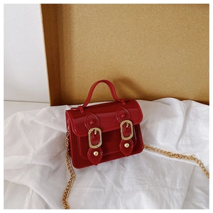 Detail of red patent leather mini bag with double buckles and golden chain strap