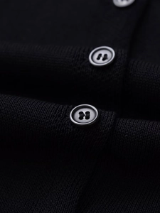 Close-up of elegant black knitted cardigan showing texture and round metallic buttons