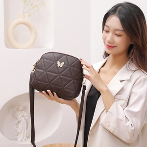 Deep brown quilted crossbody shell bag with golden butterfly ornament on female model