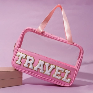 Detailed view of pink PVC makeup bag with gold TRAVEL glitter lettering and PU base