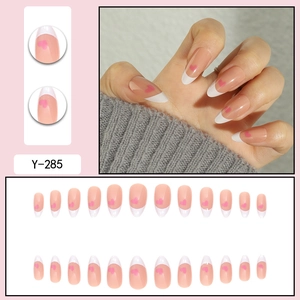 Gros plan d'ongles en amande avec pointes blanches et motifs de cœurs roses.