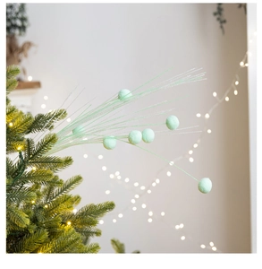 Close-up of mint green plush balls and silver glitter branches on a Christmas tree