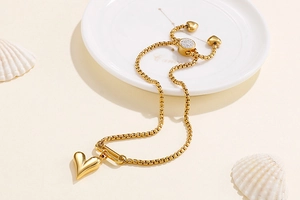 Detail of adjustable gold heart bracelet with pavé accents on warm beach decor background