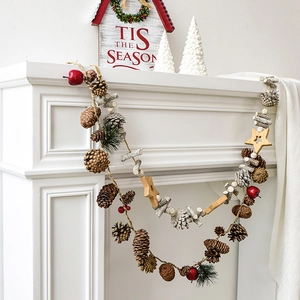 Christmas garland with pine cones, red berries and wooden stars on a white fireplace