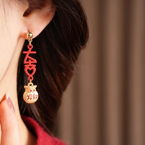 Detailed close-up of vintage enamel tassel earrings with lucky bag and xi character