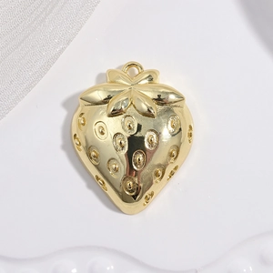 Macro shot of a golden strawberry pendant with textured seeds on a white fabric surface