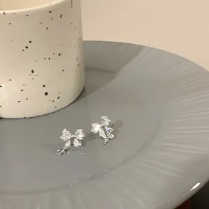 Détail de boucles d'oreilles nœud avec des zircons clairs et un petit pendentif étoile