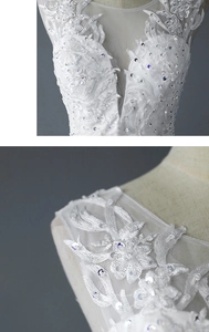 Detail of white wedding dress featuring intricate lace leaf embroidery and shiny sequins