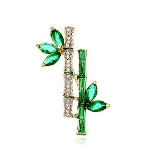 Detailed close-up of golden bamboo brooch with green enamel leaves and clear crystals