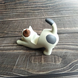 Detail of creative resin cat figurine phone holder showing stretching cat on wood background