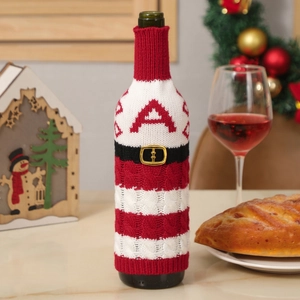 Knitted Christmas wine bottle cover with red stripes and belt design on a festive table