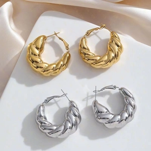 Chunky twisted gold and silver stainless steel hoop earrings for women on silk background