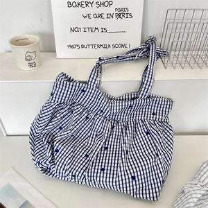 Detail of blue gingham tote bag featuring floral embroidery and ruffled drawstring closure