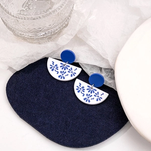Detailed view of blue and white porcelain pattern earrings on acrylic geometric pendants