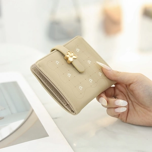 Close-up of beige quilted PU leather short wallet featuring a floral metal buckle