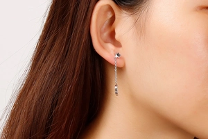 Close-up of silver star and moon drop earrings with thin metal chains on model