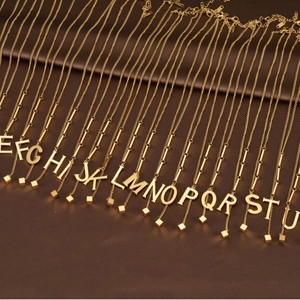 Elegant gold titanium steel alphabet pendant necklaces displayed on leather background