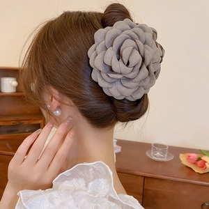 Detail of taupe fabric camellia flower hair clip worn in a classic French bun style