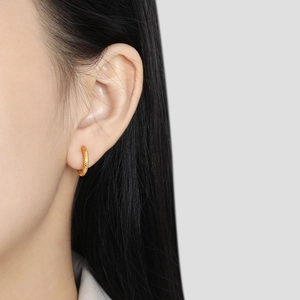 Minimalist gold plated stainless steel twisted hoop earrings worn on a model's ear
