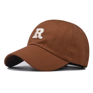 Detail of embroidered white towel letter R on a brown cotton twill baseball cap