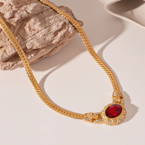 Detail of vintage gold-tone chain necklace featuring a red oval gemstone and rhinestones
