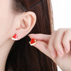 Detailed view of red and white enamel Santa hat earrings on model for Christmas