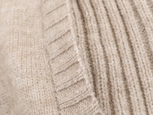 Macro view of beige ribbed knit texture and soft wool blend stitching details