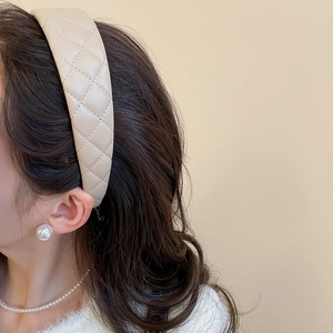 Close-up of a beige quilted faux leather headband with elegant diamond stitching