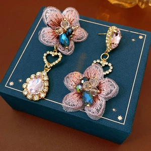 Macro shot of pink fabric flower earrings with blue beads and heart-shaped crystals
