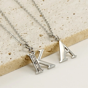 Detail of silver titanium steel necklaces with crystal K and polished A letter pendants