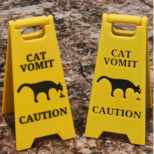 Yellow plastic stand with Cat Vomit Caution sign and feline silhouette graphic