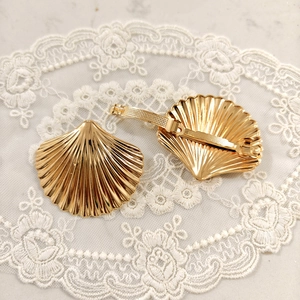 Detailed view of golden scallop hair clips with textured metal surface on lace background