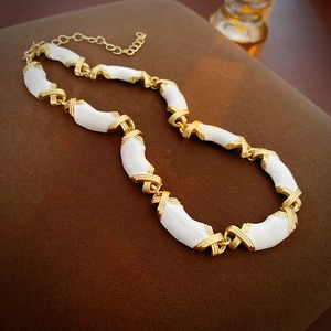 Macro shot of gold-plated metal and white enamel X-shaped interlocking necklace links